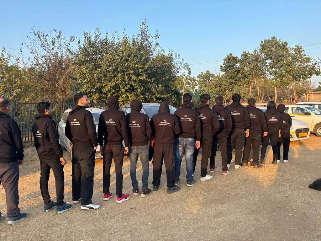 D2i Technology employees lined up outdoors wearing matching team jackets