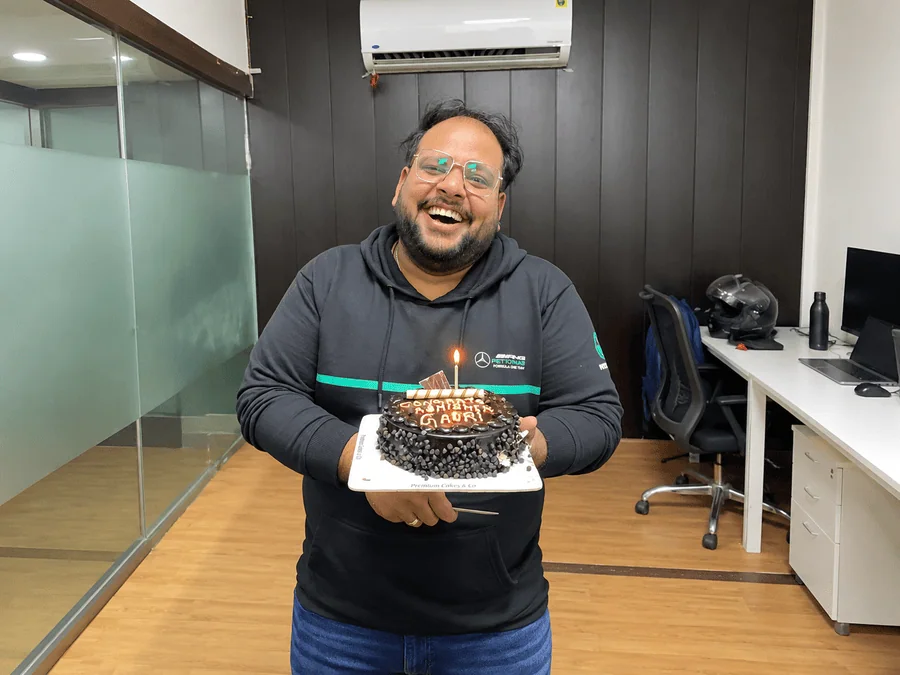 Abhishek Saraswat holding a birthday cake during an office celebration.