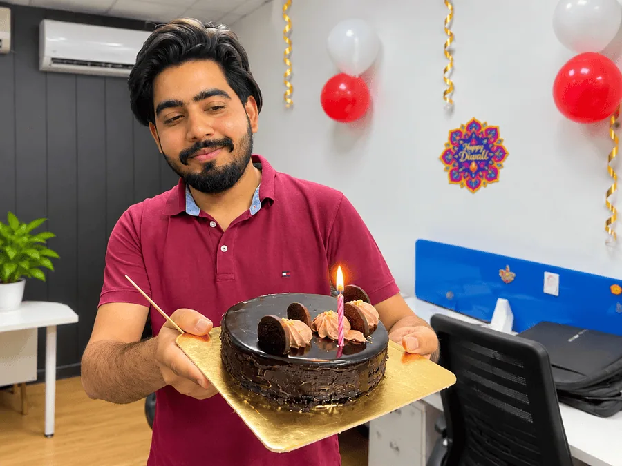Anas Saifi holding a birthday cake during an office celebration.