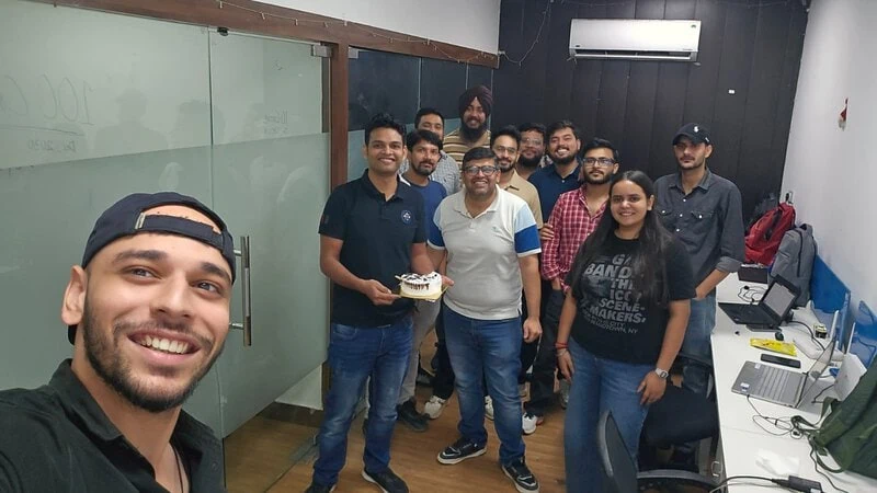 D2i Technology team celebrating Ashish Kumar’s birthday with a cake in the office.