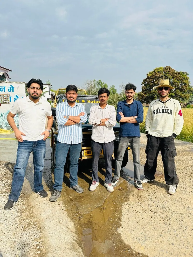 Five men by jeep: Five men standing in a row beside a jeep on a rural road, arms crossed.