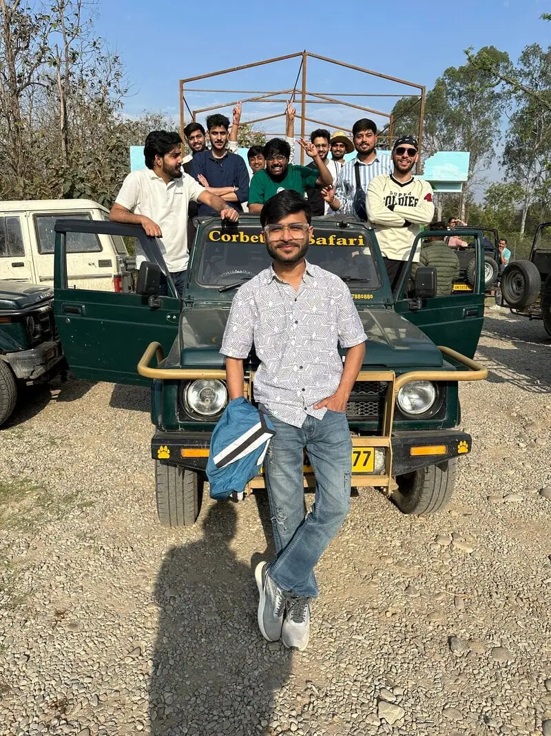 Group on Corbett Safari jeep: Group of men posing on and around a jeep labeled "Corbett Safari" in a gravel lot, one man leaning against the front.