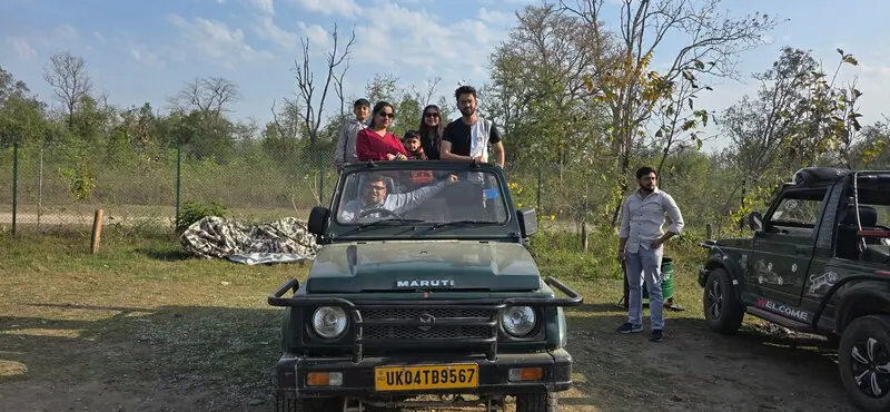 Safari jeep, family group: Family standing in an open Maruti Gypsy safari jeep at a forest reserve, with the driver waving out the window.