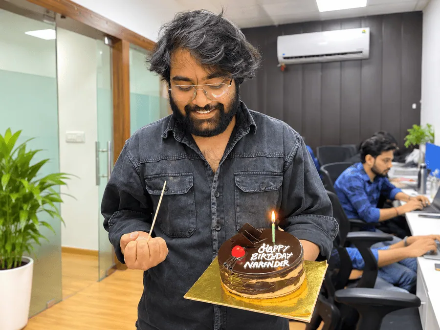Narender Yadav holding a birthday cake during an office celebration.