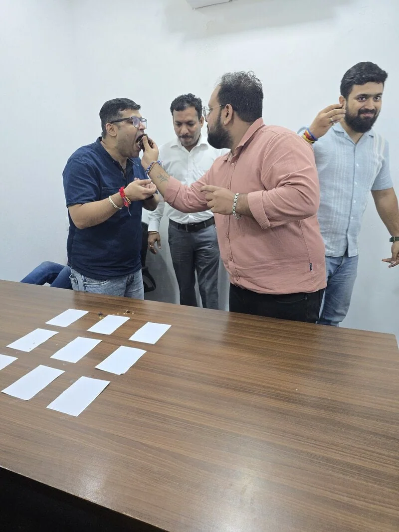 D2i Technology team members celebrating together in the office with cake.
