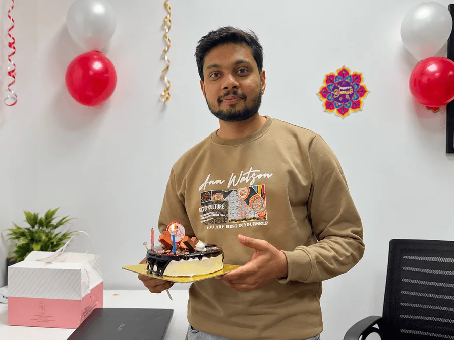 Ujjwal Sharma holding a birthday cake during an office celebration.